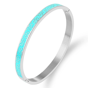 Detail view of silver stainless steel bangle featuring light blue daisy enamel patterns