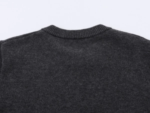 Macro detail of the charcoal grey knit sweater featuring a ribbed crew neck and soft texture
