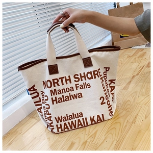 Detail der cremeweißen Canvas-Tragetasche mit brauner Hawaii-Typografie und Ledergriffen