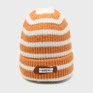Detail of the thick orange and white striped knit beanie with an ADER leather patch