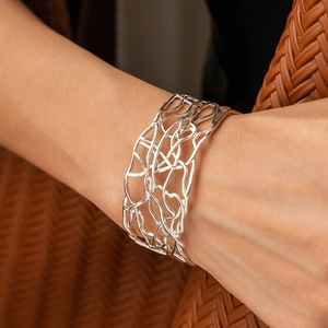 Close-up of polished silver wide hollow intertwined bangle with modern fluid design