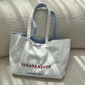 Detail der roten Stickerei auf weißem Canvas-Shopper mit blau gestreiftem Futter