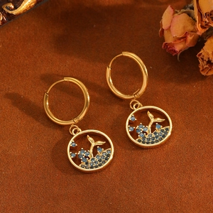 Golden dolphin tail hoop earrings with blue gemstone wave charm on brown velvet