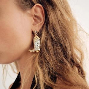Unique mixed-metal star and boot earrings in gold and silver, shown on a female model
