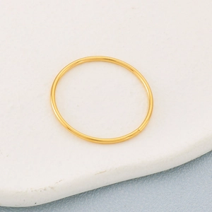 Bague ouverte minimaliste en acier inoxydable doré sur pierre blanche et fond bleu texturé
