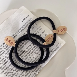 Détail de trois élastiques à cheveux noirs sans couture avec étiquettes en papier kraft