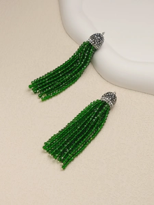 Detail of green beaded tassel earrings with silver crystal cap on stone pedestal