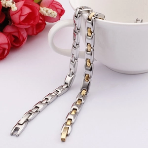 Detail of two-tone gold and silver link bracelet draped on a white ceramic cup