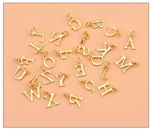 Macro view of gold-plated 925 sterling silver alphabet charms on a pink background