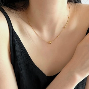 Close-up of minimalist gold snake chain necklace with beads worn on a model