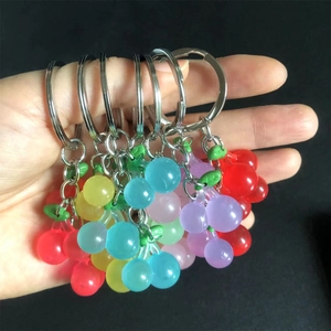 Close-up of colorful translucent resin cherry keychains held in hand with metal rings
