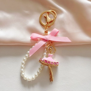 Close-up of ballet girl keychain with pink rhinestones, enamel dress and pearl chain