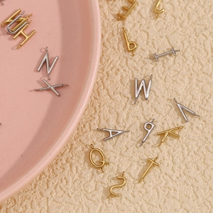 Detailed shot of 18K gold and silver plated DIY letter pendants on a minimalist tray