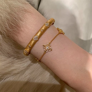 14k gold plated clover bracelet with zirconia stones and brushed metal finish on model