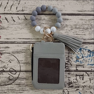 Close-up of grey silicone beaded wristlet with matching leather card wallet and tassel