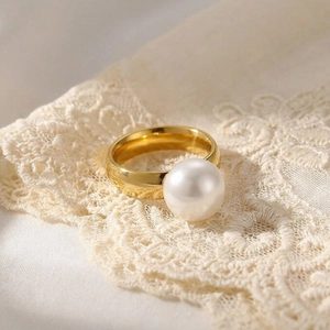 Elegant gold stainless steel pearl ring for women on a vintage beige lace background