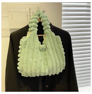 Detail of mint green plush tote bag with vertical stripes hanging on a hanger