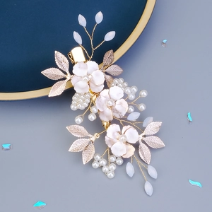 Detail of floral hair clip with pink flowers, white pearls and golden leaves on blue plate