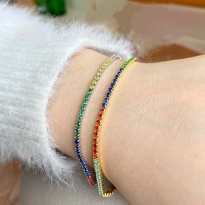 Close-up of rainbow zircon tennis bracelets in gold and silver finishes on a model's wrist