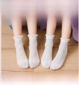 Close-up of baby mesh socks with floral embroidery and satin bow on wooden floor
