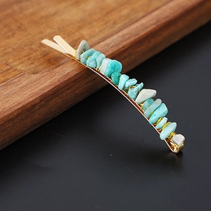 Close-up of golden metal hair clip with irregular turquoise natural stone fragments