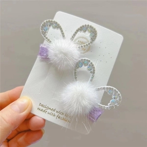 Detail of plush rabbit ear hair clips with sparkling rhinestones and purple ribbon wrap