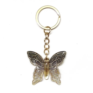 Detail of gradient butterfly keychain with golden wing textures and metallic ring