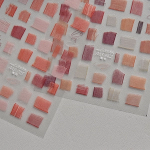 Close-up of thin nail stickers with vintage lace and gauze texture in red tones