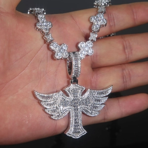 Macro shot of silver winged cross pendant with cubic zirconia on cuban link chain