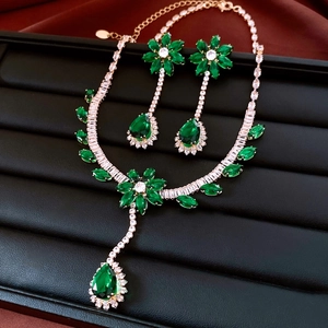 Detailed view of emerald green flower necklace and earring set with white crystals