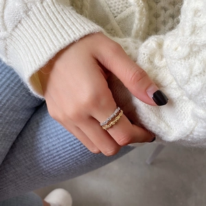 Detail showing gold and silver twisted rope rings stacked on a model in winter knitwear