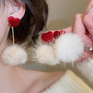 Gros plan de boucles d'oreilles cœur avec pompon blanc sur mannequin pour l'hiver