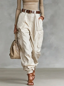 Detail of high-waist cargo trousers with multiple pockets and a matching brown leather belt