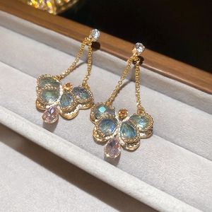 Macro shot of colorful crystal butterfly earrings with teardrop pendants on velvet