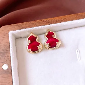 Elegant red velvet gourd studs with gold edges and starry crystals in a wooden box