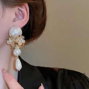 Close-up of vintage flower drop earrings with white pearls and gold metal tassels