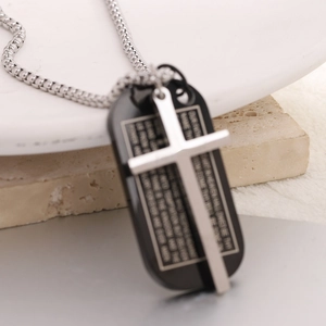 Silver cross and black military dog tag necklace with engraved scripture on stone background