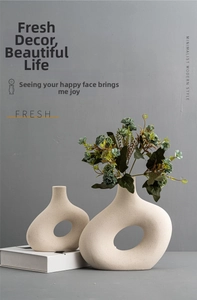 Detail of minimalist ceramic vases set with matte pebble texture and hollow center design