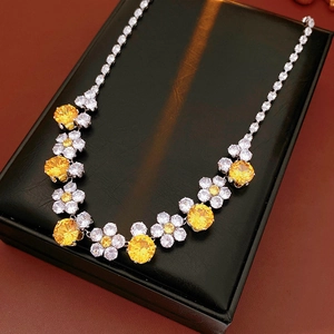 Detailed view of flower necklace with yellow zircon and white gems on black leather box