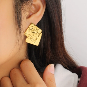 Close-up of 18K gold plated square earrings with hammered texture on female model