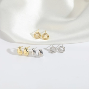 Set of gold and silver teardrop earrings and circular zircon studs on white silk fabric