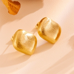 Detail of vintage gold matte geometric stud earrings with a brushed metallic texture
