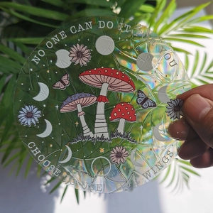 Close-up of a holographic suncatcher sticker with mushrooms and moon phases