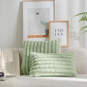 Detail of green faux rabbit fur pillows with striped texture on a cozy beige sofa