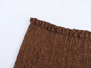 Detailed view of deep brown smocked fabric texture with elastic shirring and ruffled edges