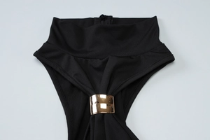 Detail of black dress featuring high neck with gold metal accents and back zipper closure