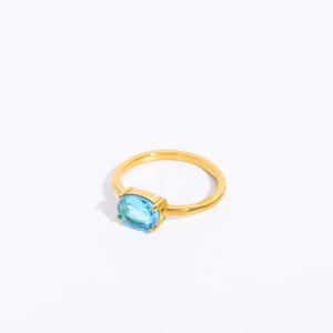 Detail of gold stainless steel ring featuring a vibrant oval blue birthstone setting
