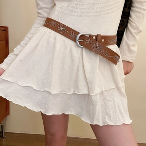 Détail de ceinture en cuir marron avec rivets argentés et boucle à ardillon simple