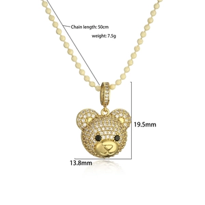 Detailed view of gold teddy bear pendant with white zircon and black gemstone eyes