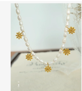 Detailed close-up of a pearl necklace with golden daisy flower pendants and oval pearls